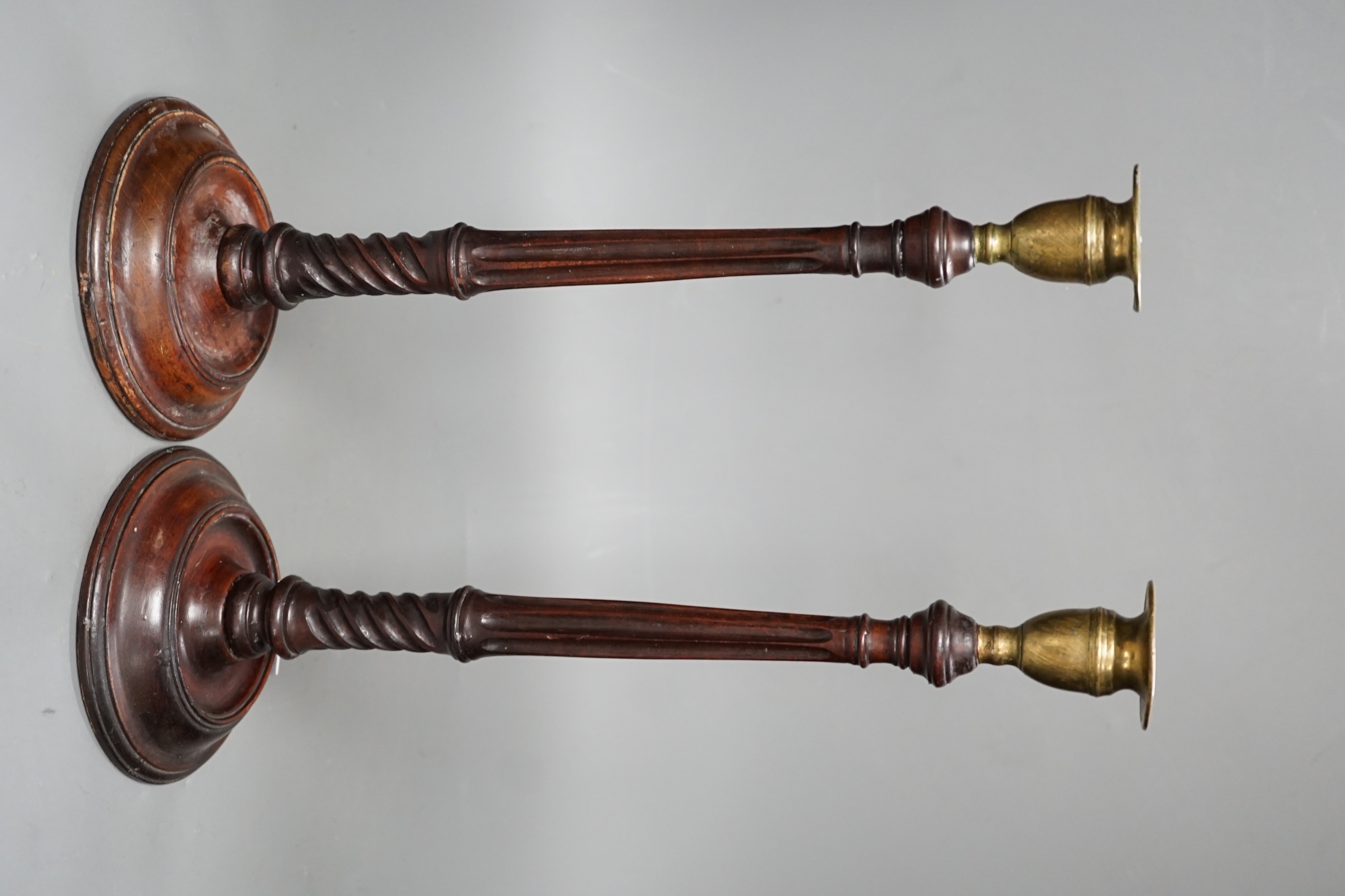 A pair of George III style carved mahogany candlesticks, with brass sconces, 38cms high